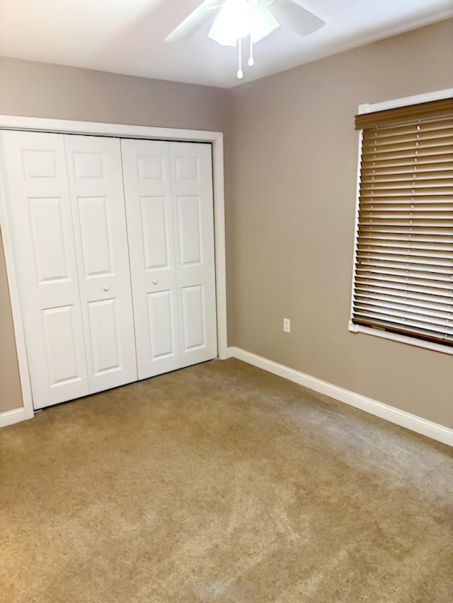 unfurnished bedroom featuring ceiling fan, light carpet, and a closet