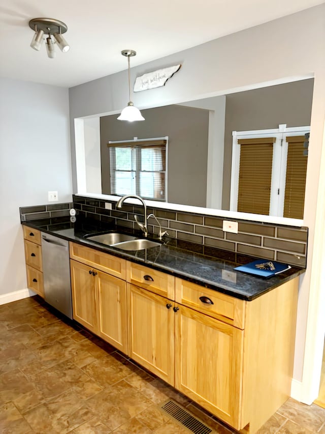 kitchen featuring backsplash, dark stone counters, sink, hanging light fixtures, and stainless steel dishwasher