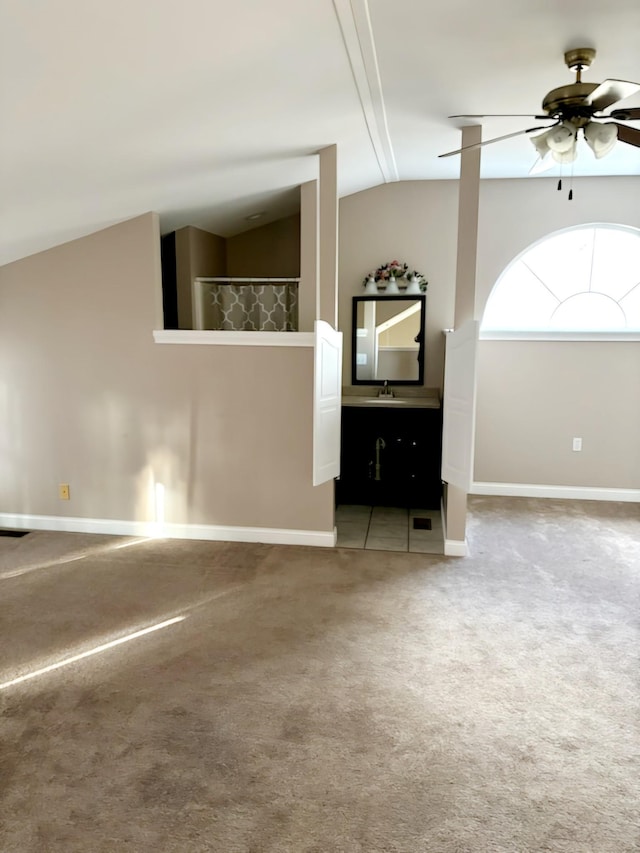 carpeted empty room featuring ceiling fan, lofted ceiling, and sink