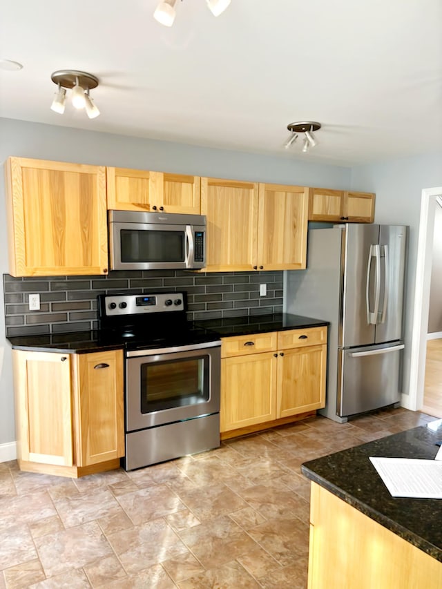 kitchen with decorative backsplash, light brown cabinets, stainless steel appliances, and dark stone counters