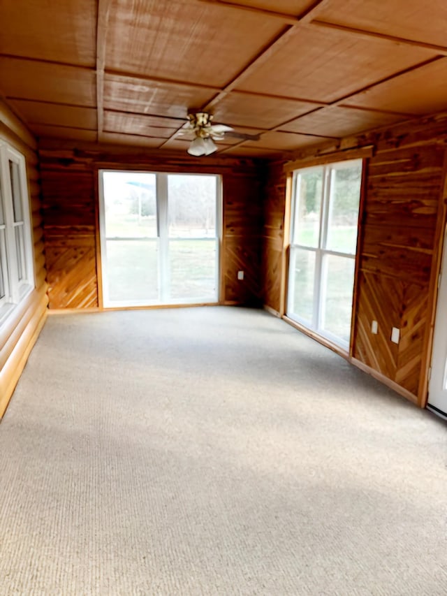 unfurnished living room with carpet floors, ceiling fan, wooden walls, and wood ceiling