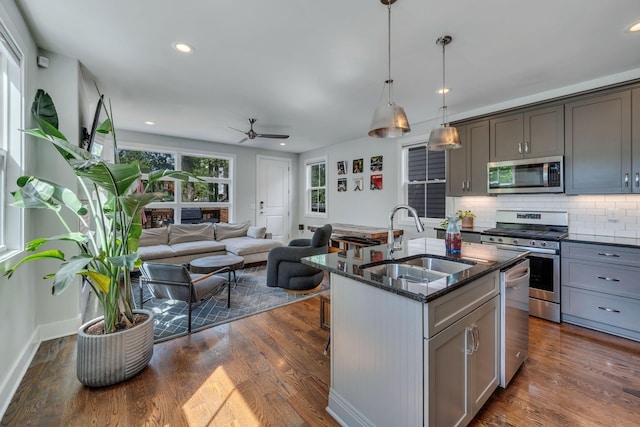 kitchen featuring stainless steel appliances, a kitchen island with sink, gray cabinetry, and sink