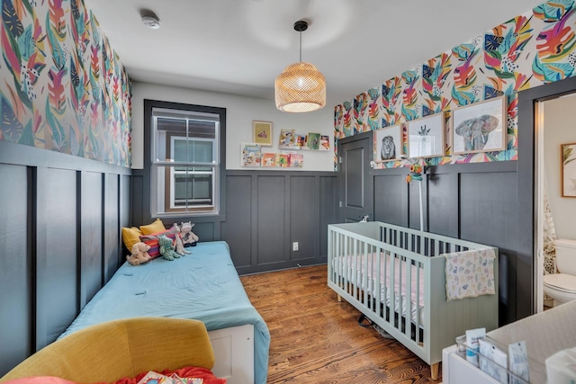 bedroom with a nursery area and wood-type flooring