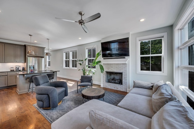 living room with ceiling fan, dark wood-type flooring, and a brick fireplace