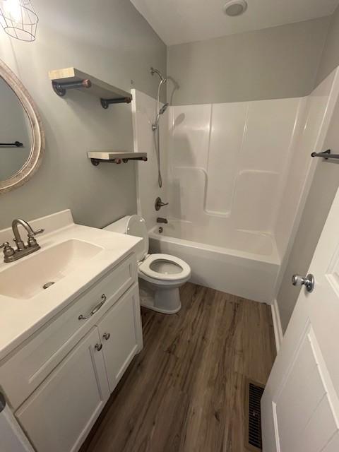 full bathroom with hardwood / wood-style floors, vanity,  shower combination, and toilet