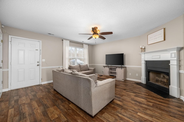 living room with a textured ceiling, ceiling fan, and dark wood-type flooring