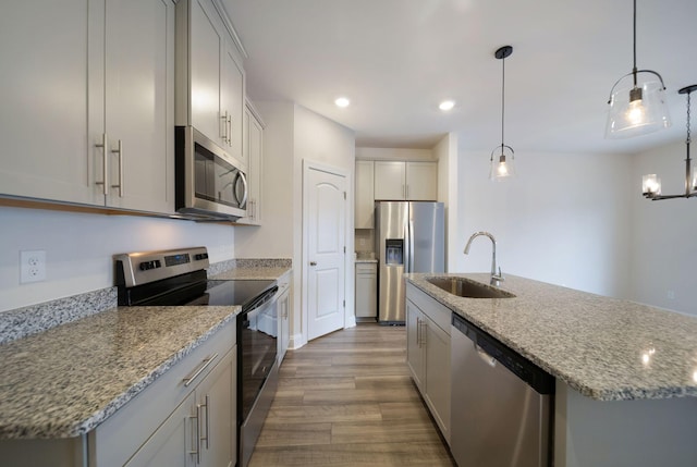 kitchen with sink, an island with sink, decorative light fixtures, and appliances with stainless steel finishes