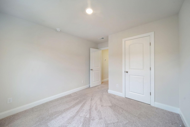 unfurnished bedroom featuring light colored carpet and a closet