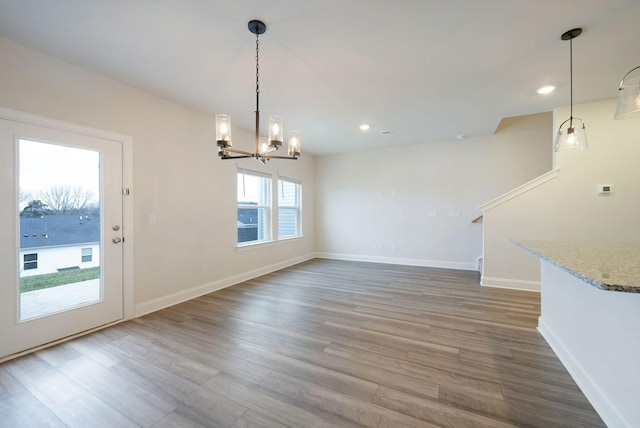 unfurnished dining area featuring a water view, wood-type flooring, and an inviting chandelier