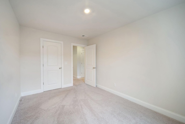 unfurnished bedroom with light carpet and a closet