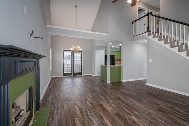 unfurnished living room with ceiling fan with notable chandelier, dark hardwood / wood-style flooring, and a towering ceiling