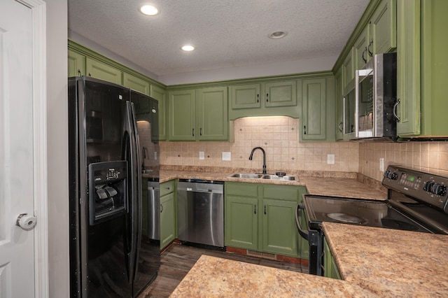 kitchen with sink, dark wood-type flooring, green cabinets, a textured ceiling, and black appliances