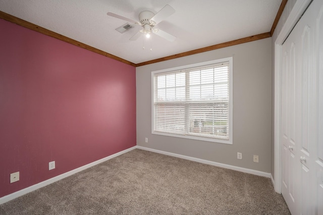 carpeted empty room with ceiling fan and ornamental molding