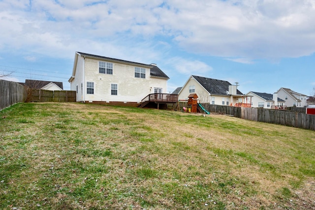 rear view of house with a playground, a wooden deck, and a yard