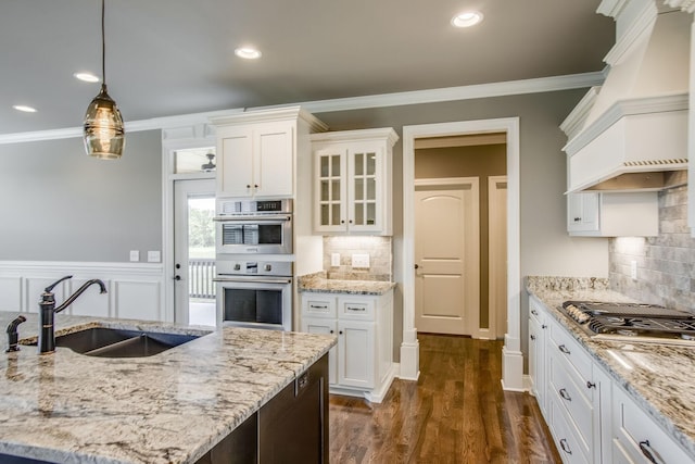 kitchen featuring sink, custom exhaust hood, decorative light fixtures, stainless steel appliances, and white cabinets