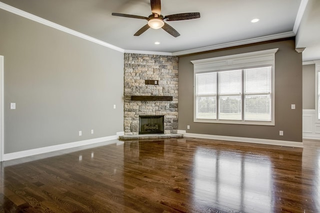 unfurnished living room with ornamental molding, a stone fireplace, wood-type flooring, and ceiling fan