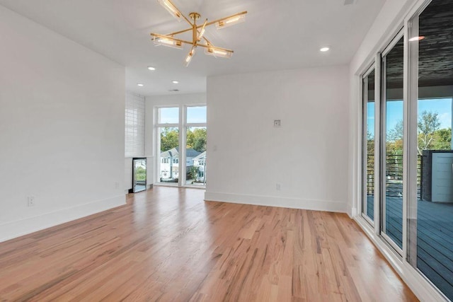 spare room with a notable chandelier and light wood-type flooring