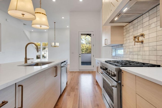 kitchen featuring backsplash, sink, hanging light fixtures, wall chimney exhaust hood, and stainless steel appliances