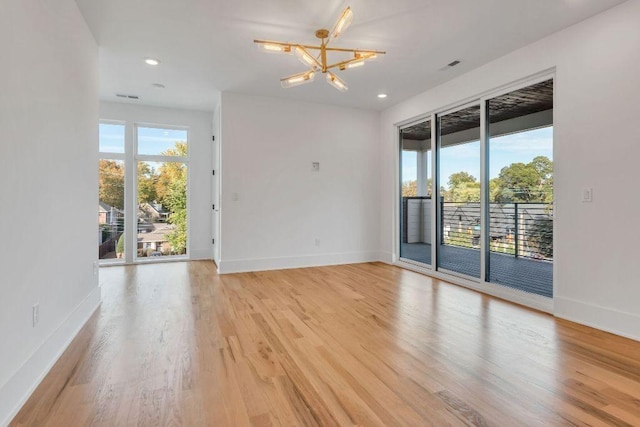 unfurnished room with a chandelier and light hardwood / wood-style floors