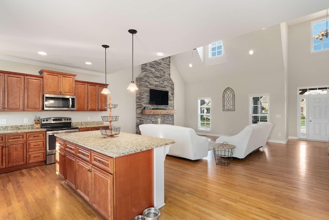 kitchen featuring pendant lighting, a towering ceiling, stainless steel appliances, light hardwood / wood-style floors, and a kitchen island