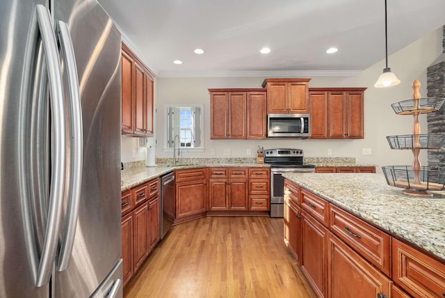 kitchen with decorative light fixtures, sink, light stone counters, light hardwood / wood-style floors, and stainless steel appliances