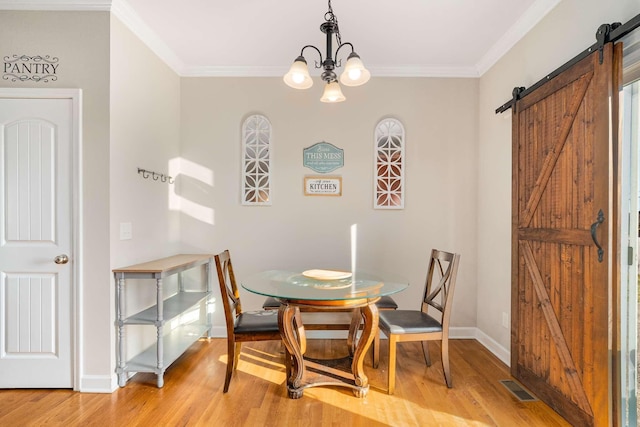 dining room with crown molding, a barn door, hardwood / wood-style floors, and a notable chandelier