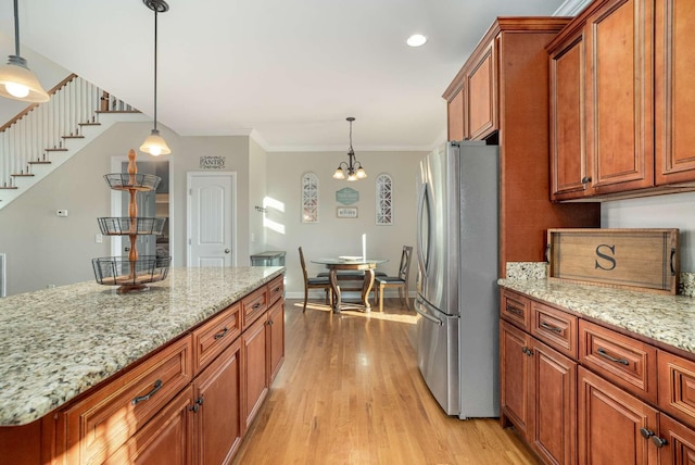 kitchen featuring crown molding, hanging light fixtures, stainless steel fridge, a notable chandelier, and light stone countertops