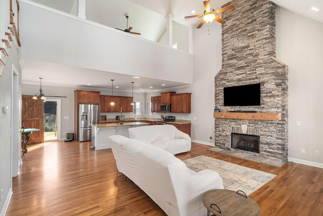 living room with hardwood / wood-style floors, a fireplace, a high ceiling, ornamental molding, and ceiling fan