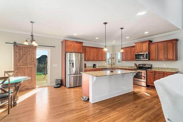 kitchen with a breakfast bar, appliances with stainless steel finishes, hanging light fixtures, a center island, and a barn door