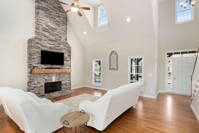 living room with ceiling fan, a fireplace, a wealth of natural light, and a high ceiling