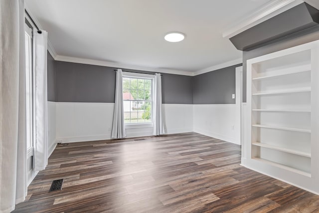 spare room featuring dark hardwood / wood-style floors, crown molding, and built in shelves