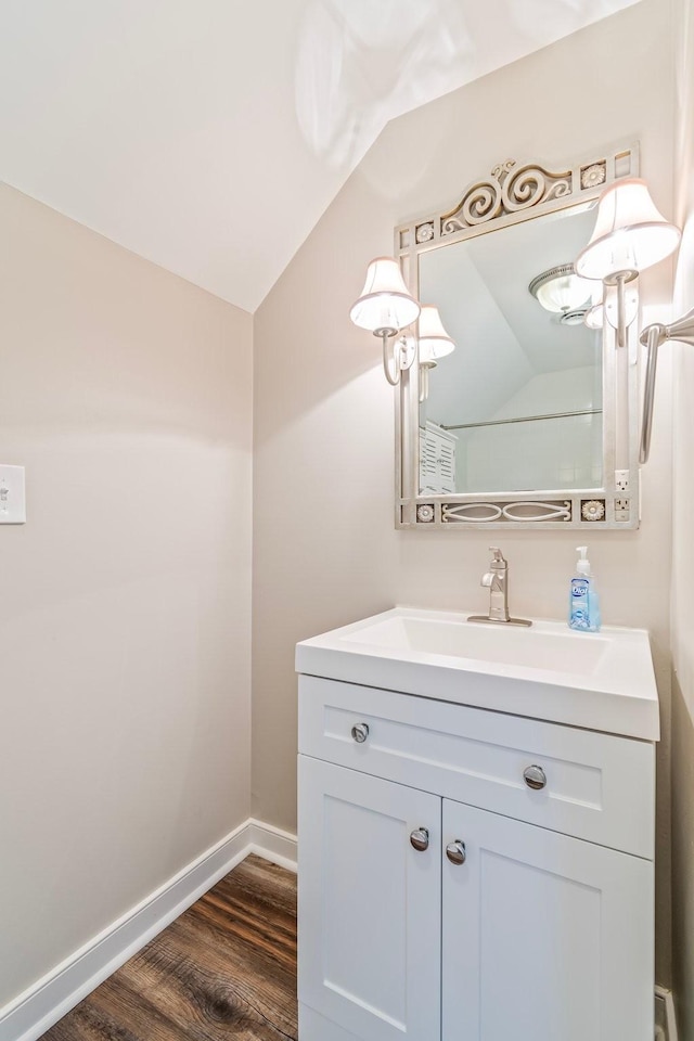 bathroom featuring hardwood / wood-style floors, vanity, and vaulted ceiling