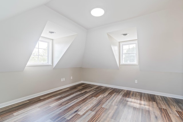 additional living space featuring vaulted ceiling, dark hardwood / wood-style flooring, and plenty of natural light