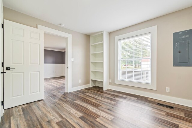 spare room featuring dark hardwood / wood-style flooring, electric panel, and built in features