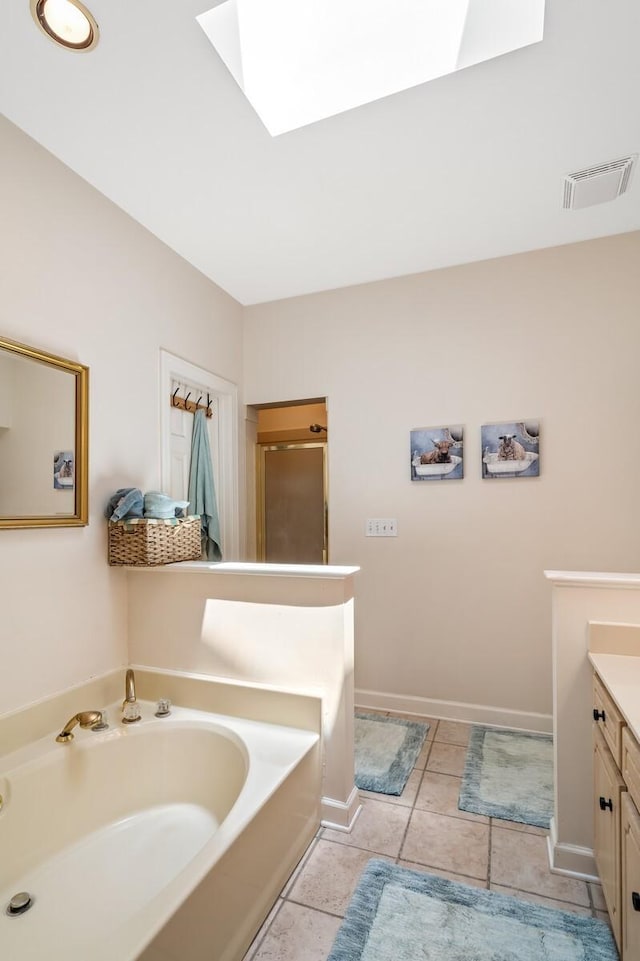 bathroom with plus walk in shower, vanity, a skylight, and tile patterned floors