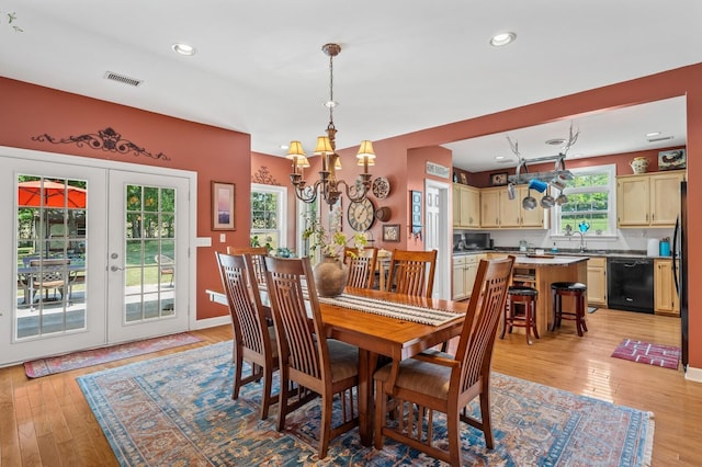 dining area featuring a chandelier, light hardwood / wood-style floors, sink, and french doors