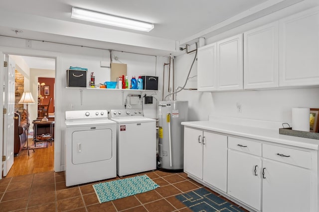 clothes washing area featuring washing machine and dryer, electric water heater, cabinets, and dark tile patterned flooring