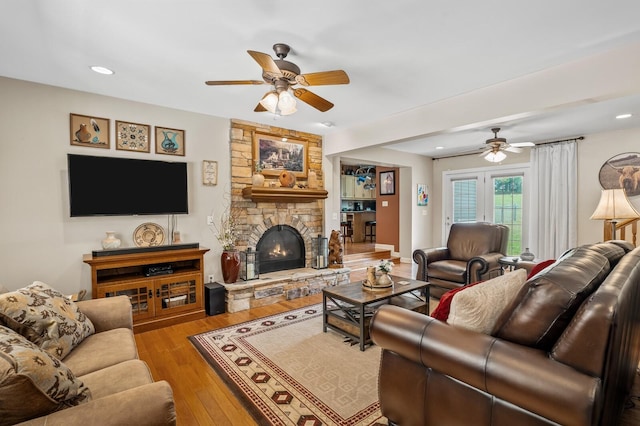 living room featuring ceiling fan, light wood-type flooring, and a fireplace