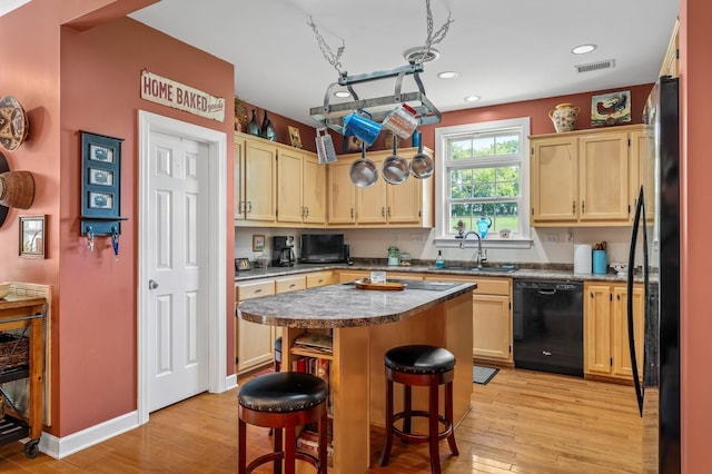 kitchen with dishwasher, sink, light hardwood / wood-style flooring, a kitchen island, and a kitchen bar