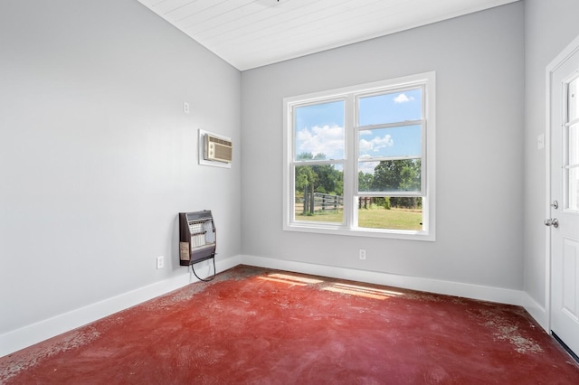 spare room with vaulted ceiling, heating unit, an AC wall unit, and plenty of natural light