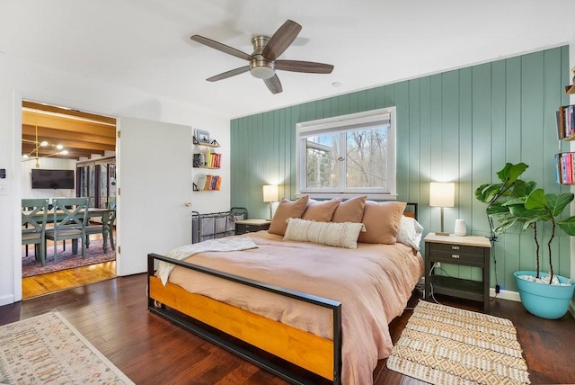 bedroom with access to outside, ceiling fan, dark wood-type flooring, and wood walls