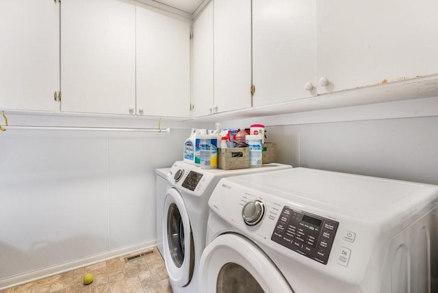 clothes washing area with washing machine and dryer and cabinets