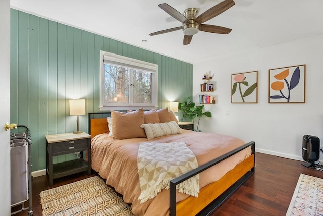 bedroom with dark hardwood / wood-style flooring, ceiling fan, and wood walls