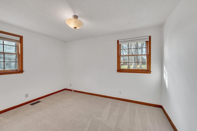 carpeted empty room featuring a textured ceiling