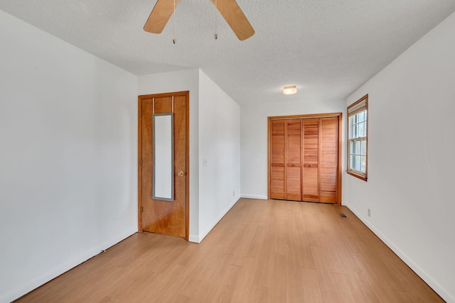 unfurnished bedroom with a textured ceiling, light wood-type flooring, a closet, and ceiling fan