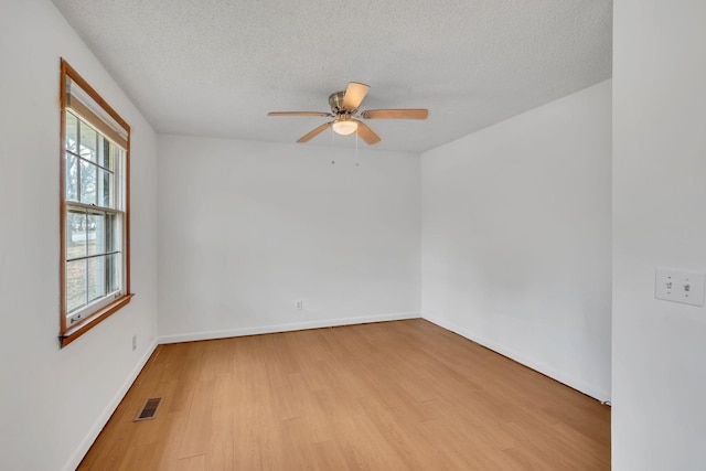 spare room with a textured ceiling, light hardwood / wood-style floors, ceiling fan, and a healthy amount of sunlight