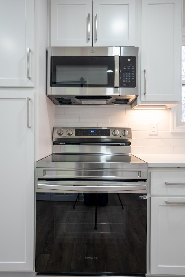 kitchen with white cabinets, appliances with stainless steel finishes, and tasteful backsplash