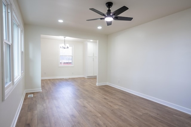 unfurnished room featuring hardwood / wood-style floors and ceiling fan with notable chandelier