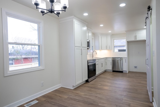 kitchen with backsplash, an inviting chandelier, white cabinets, sink, and appliances with stainless steel finishes