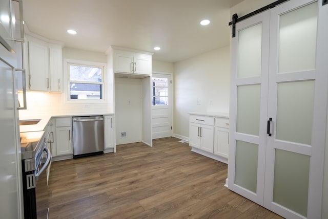 kitchen featuring dishwasher, white cabinets, electric stove, a barn door, and tasteful backsplash